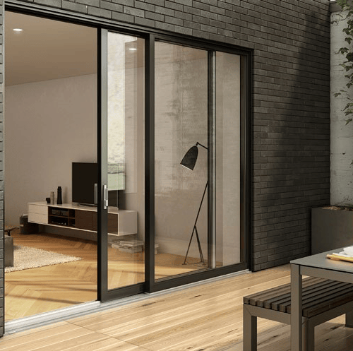 Sliding glass doors open to a modern living room with a TV and lamp, surrounded by a brick wall.